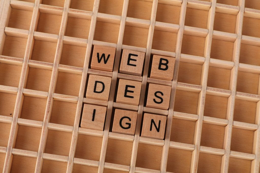 Wooden blocks spelling web design on a grid background symbolizing creative digital design concepts.