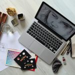 Top view of a creative workspace with a laptop, sketch supplies, and color palette.