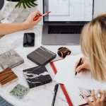 Creative professionals designing interior spaces with laptop and material samples at a modern work table.